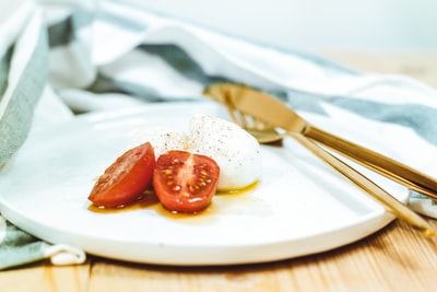 切片番茄和马苏里拉奶酪白色板旁边brass-colored刀和叉
